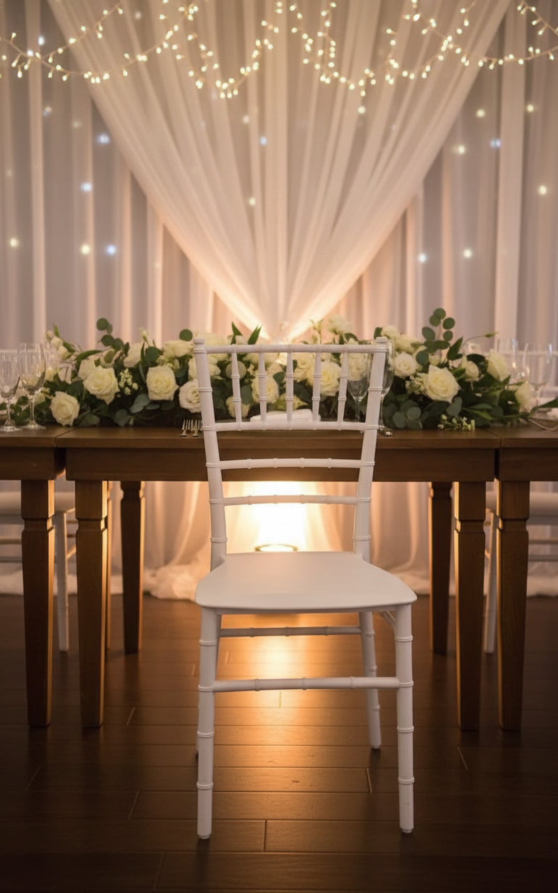 White chair next to a plant with a wooden partition in the background