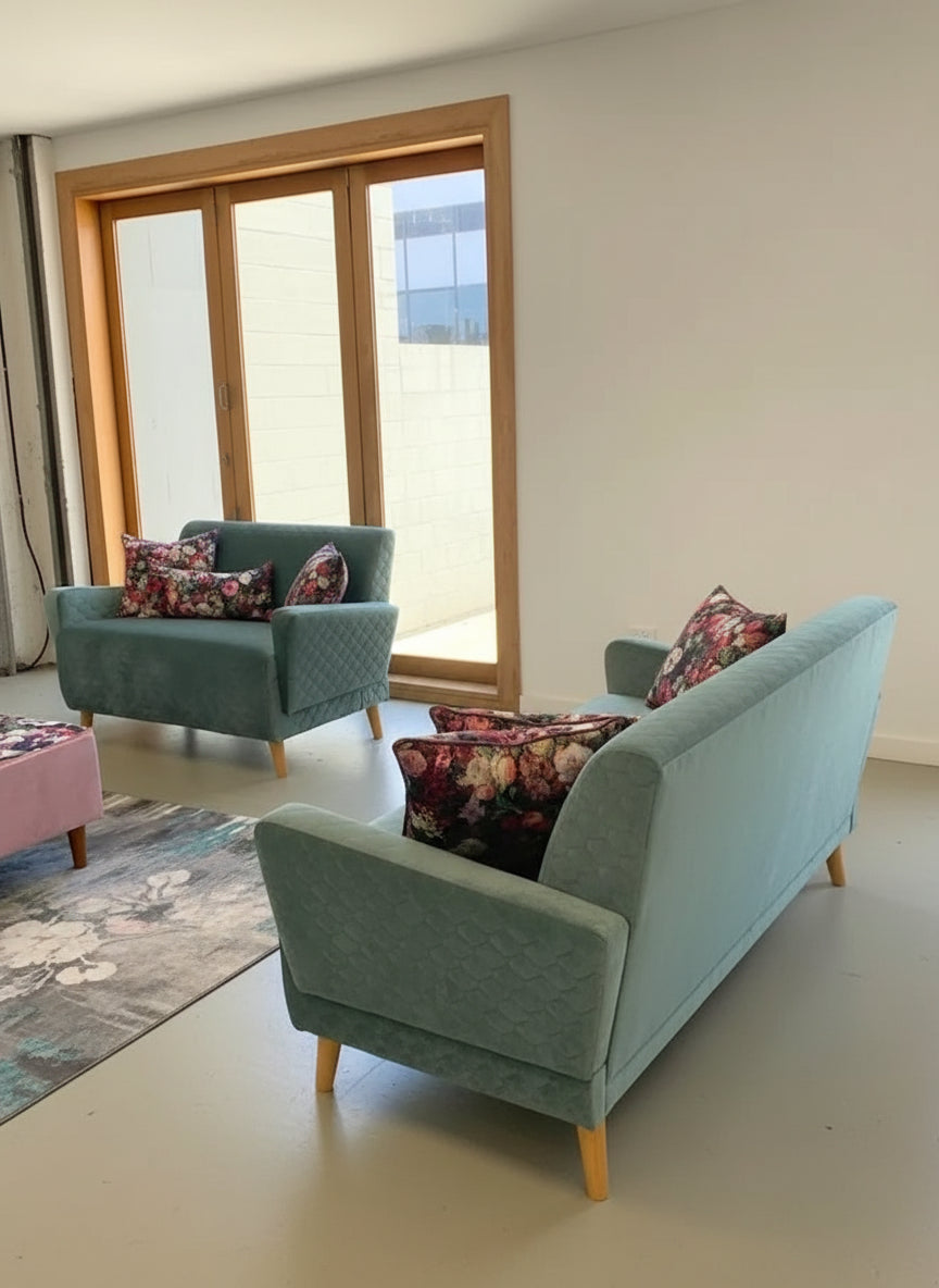 Green sofa with floral pillow in a room with large windows.
