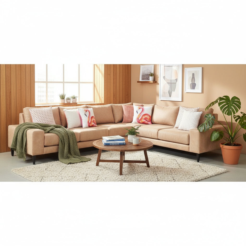 Beige sectional sofa with colorful pillows in a room with wooden walls and a small table.